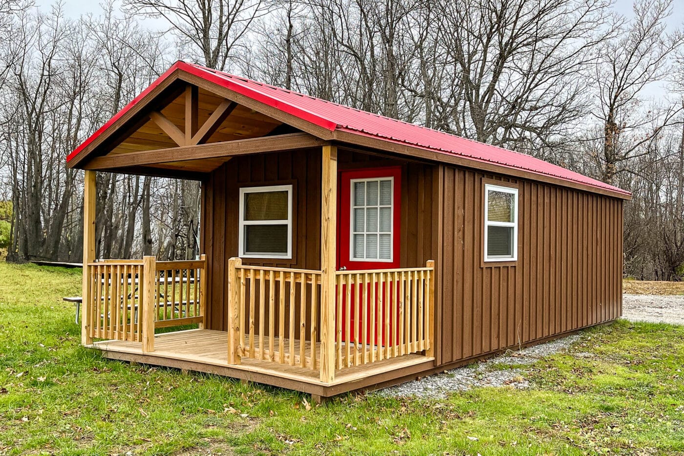 "Modern black portable shed with multiple windows, elevated on a grassy clearing."
