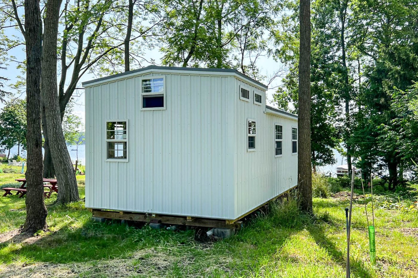 "Simple white portable shed with black trim and a slanted roof, sitting on a grassy field."