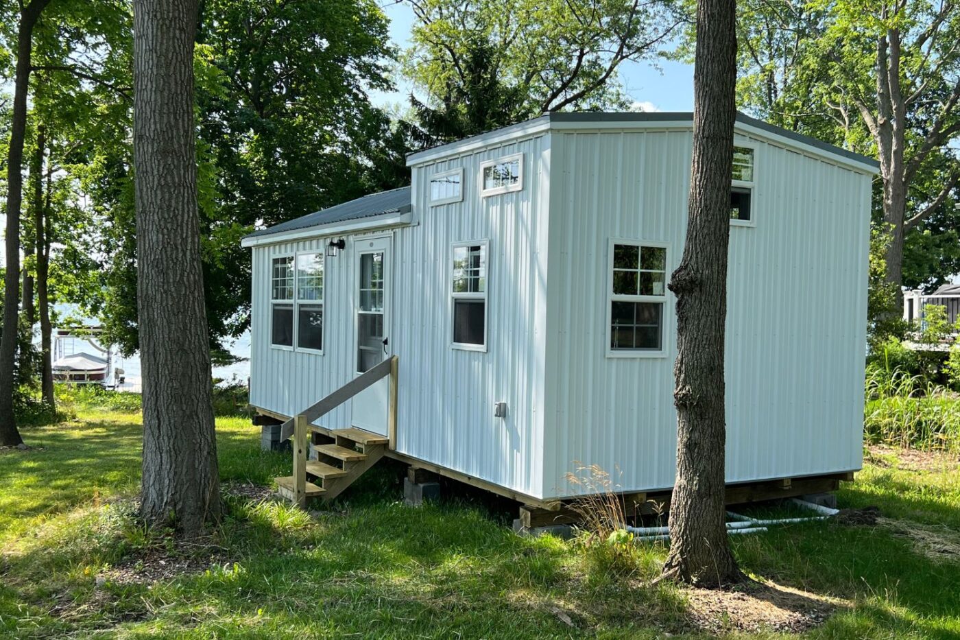 This image showcases a 14x24 modern cabin with a sleek white exterior and a metal roof